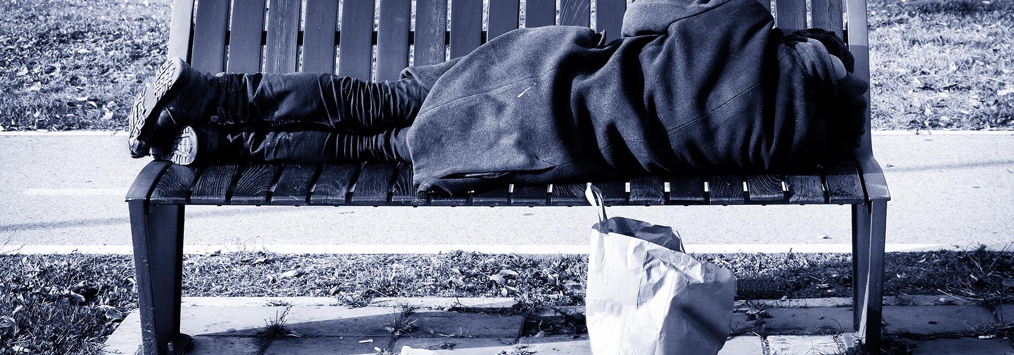 Homeless man laying on park bench